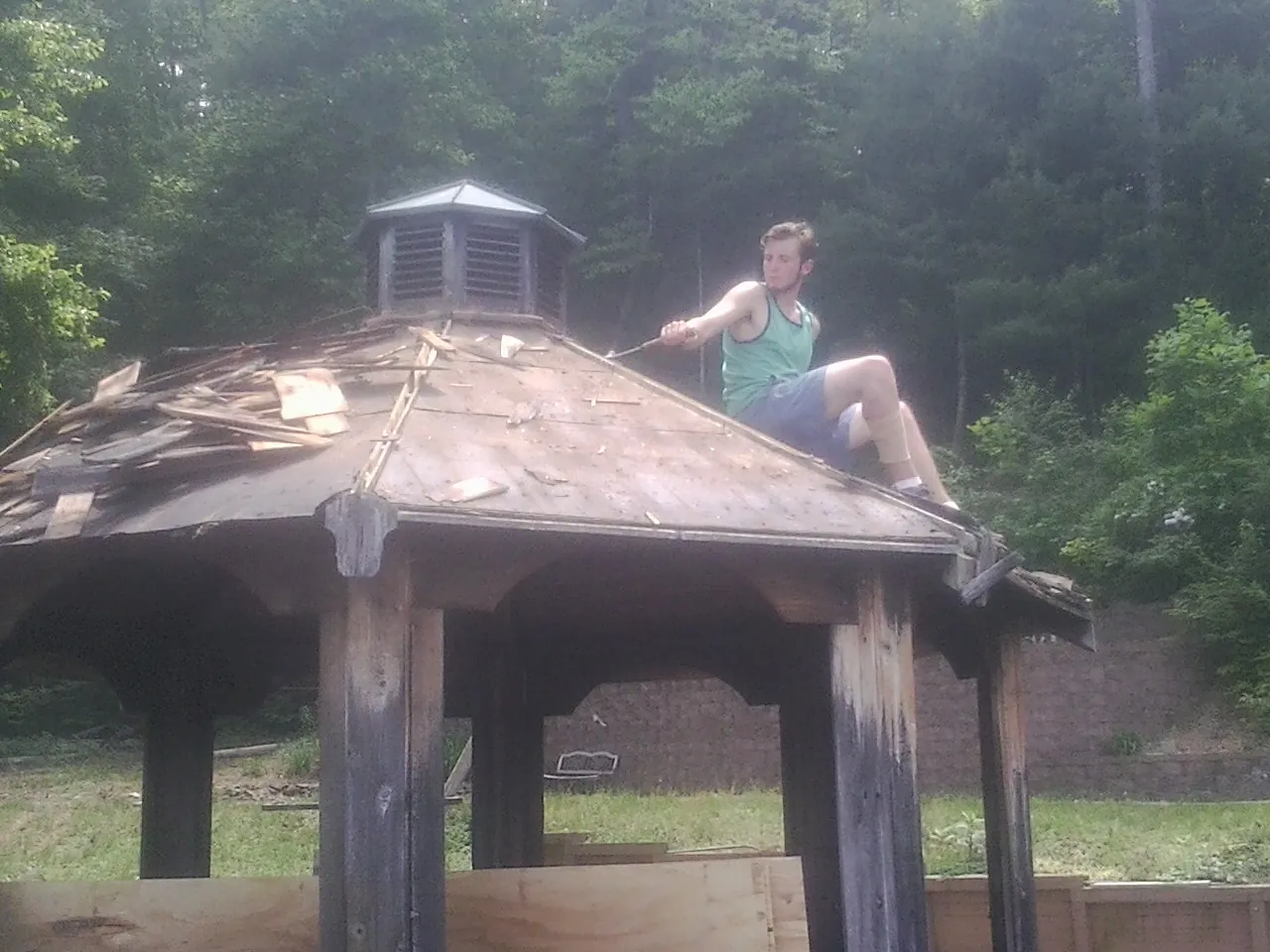 Tearing the old roof off a wooden gazebo before new shakes in Hallwood