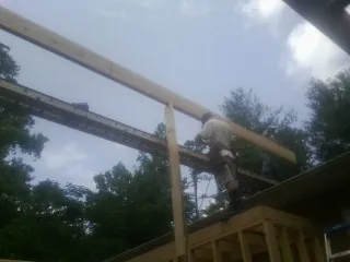 Carpenter setting a ridge beam over a new addition frame — Ice Dam Removal by Roofing Brothers in Hallwood