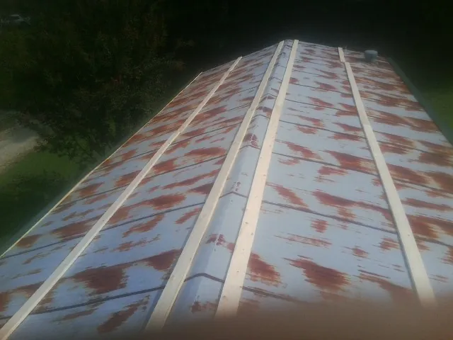 Rusted metal roof panels with new wood purlins before replacement — Storm Damage Roof Repair in Hallwood by Roofing Brothers