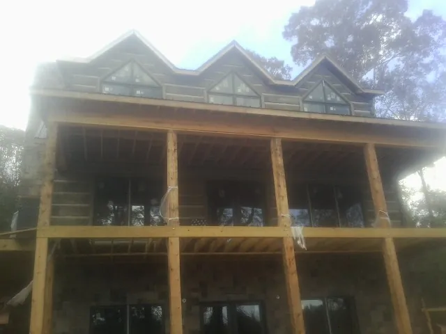 Dormers and porch framing on a large log home under construction — Roof Coating work by our crew in Hallwood