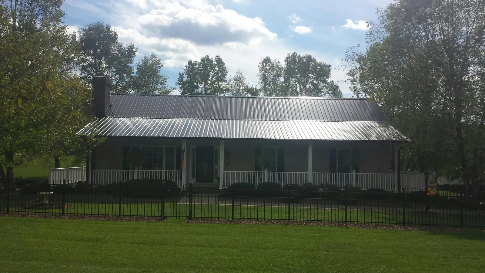 Gray metal roof on a brick ranch with a full width front porch — Gutter Guard Installation work by our crew in Hallwood