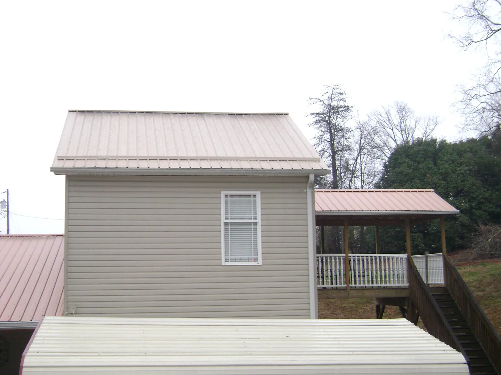 Tan metal roofs on a two story addition and attached porch, from a Roof Replacement job in Hallwood