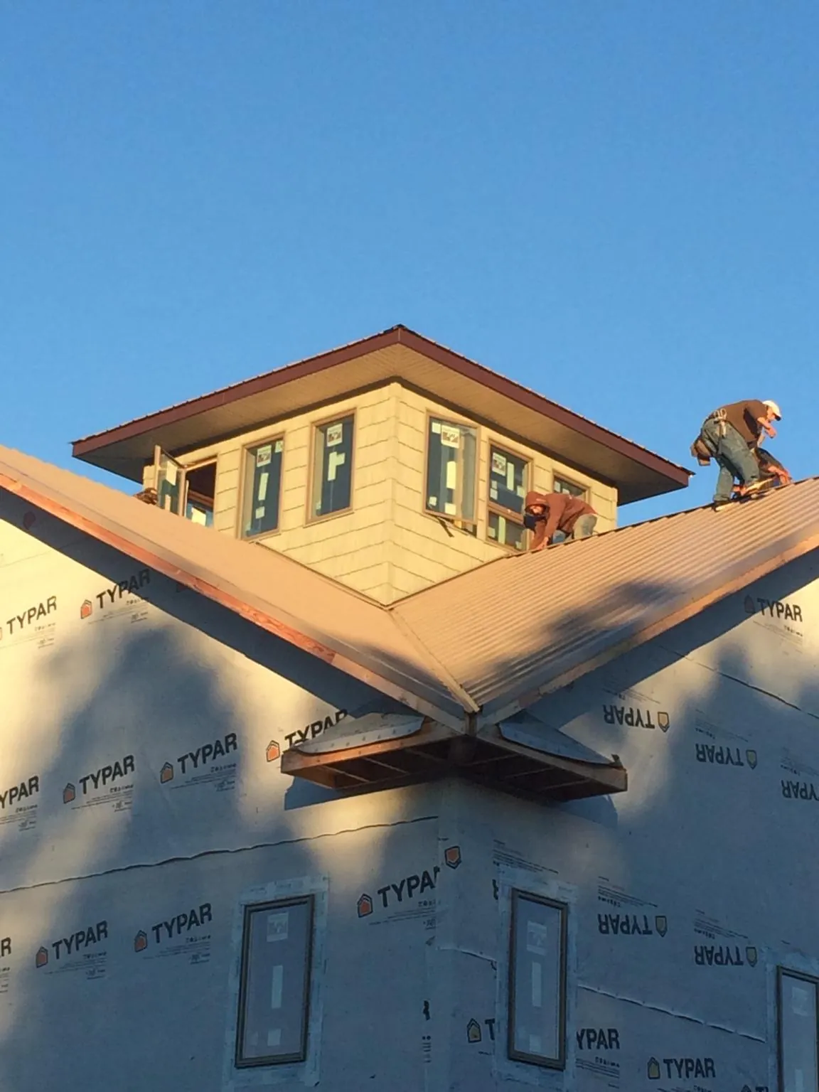 Roofers working around a rooftop cupola on a new metal roof at sunset — Roof Waterproofing in Hallwood by Roofing Brothers